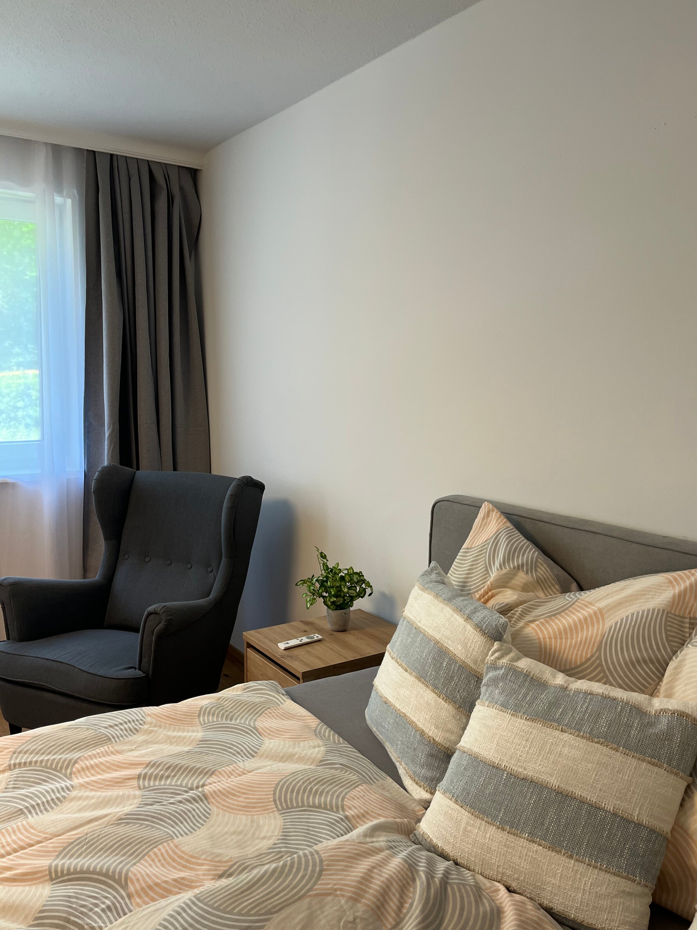 Bett mit Nachtkästchen und Ohrensessel