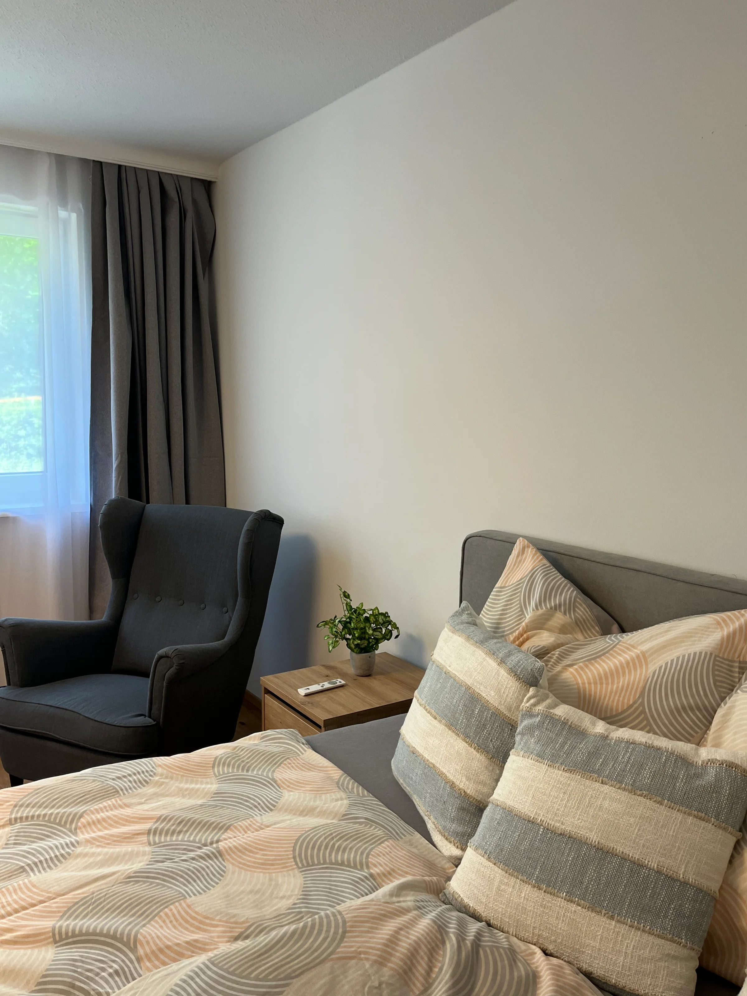 Bett mit Nachtkästchen und Ohrensessel