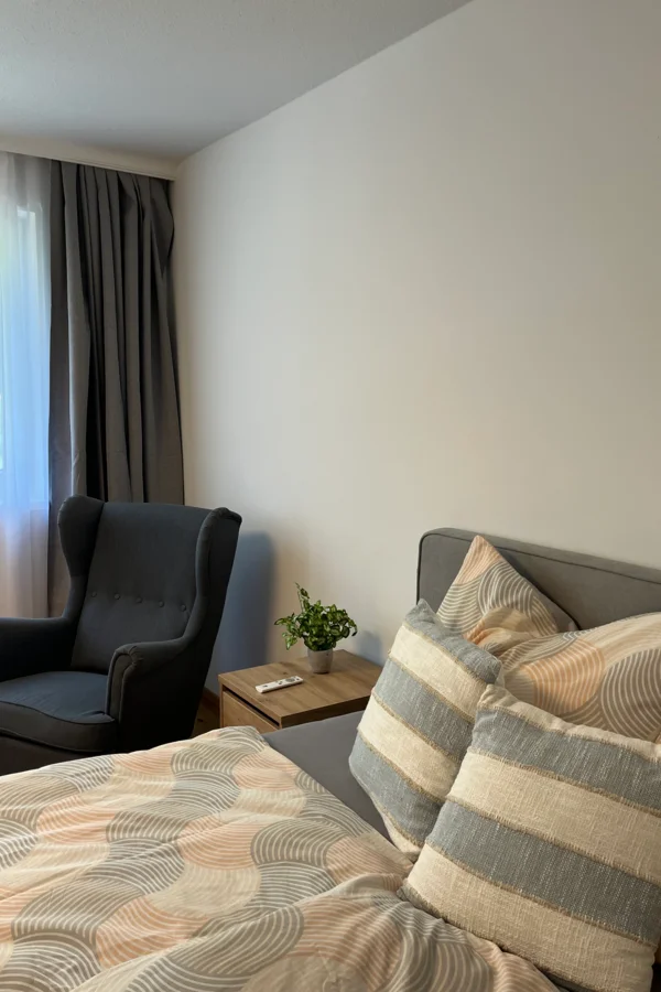 Bett mit Nachtkästchen und Ohrensessel