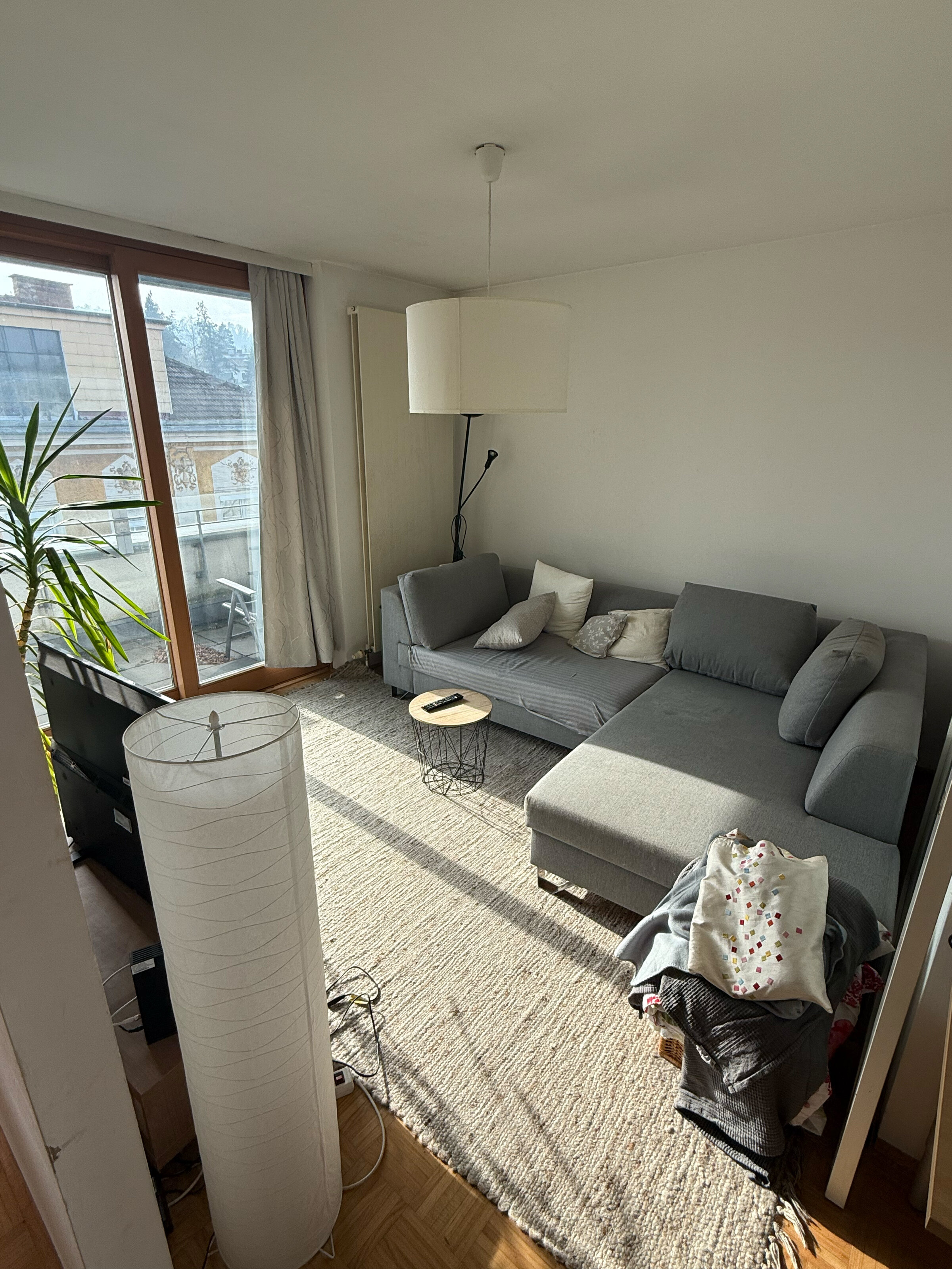 Wohnzimmer mit Schlafcouch, TV und Zugang zu Balkon