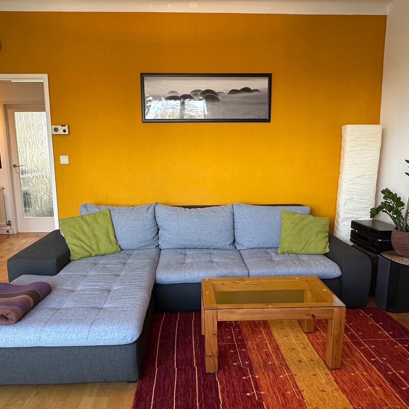 Helles Wohnzimmer mit Ecksofa & Akzentwand – 1-Zimmer Wohnung zur Kurzzeitmiete in Hietzing