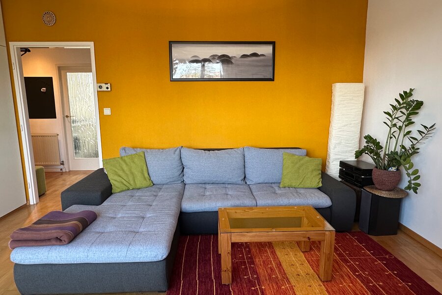Helles Wohnzimmer mit Ecksofa & Akzentwand – 1-Zimmer Wohnung zur Kurzzeitmiete in Hietzing