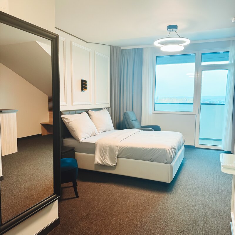 Helles Schlafzimmer mit Doppelbett & Panoramafenster – 1-Zimmer Suite zur Kurzzeitmiete, Wohnen auf Zeit für 1 bis 6 Monate in Hörsching