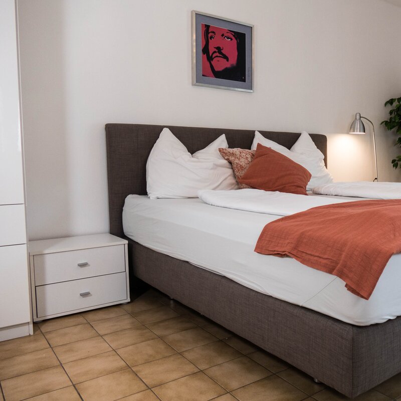 Bright bedroom with double bed & modern decor – 1-room apartment for short-term rental in Strass im Attergau