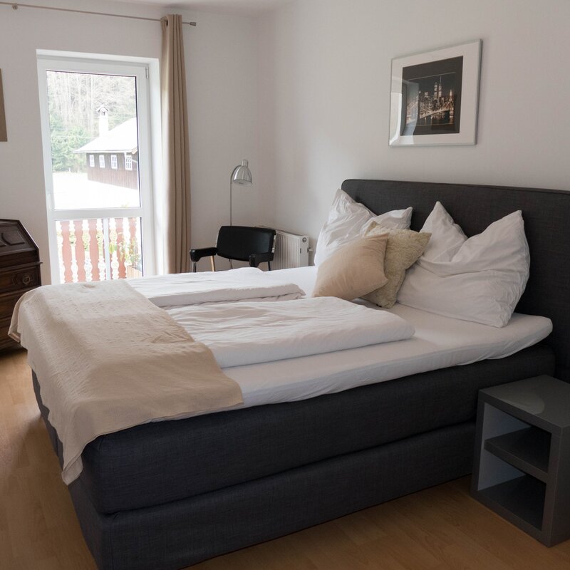 Cozy bedroom with double bed & wooden furniture – 2-room apartment for short-term rental in Strass im Attergau