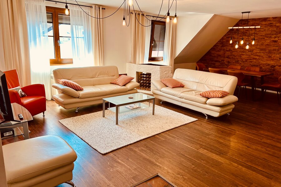 Großzügiger Wohnraum mit Esstisch und Kachelofen und Ofenbett.