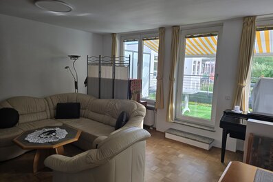 Heller und großzügiger Wohnbereich mit gemütlicher Sitzgruppe, bodentiefen Fenstern und direktem Zugang zur sonnigen Südterrasse sowie zur überdachten Loggia mit Süd-West-Ausrichtung. Der angrenzende Essbereich mit Eckbank lädt zu gemeinsamen Mahlzeiten ein. Der Raum ist lichtdurchflutet und bietet durch die Verbindung von Innen- und Außenbereich eine besonders wohnliche Atmosphäre. Warmer Parkettboden und liebevoll eingerichtete Details sorgen für ein behagliches Ambiente.