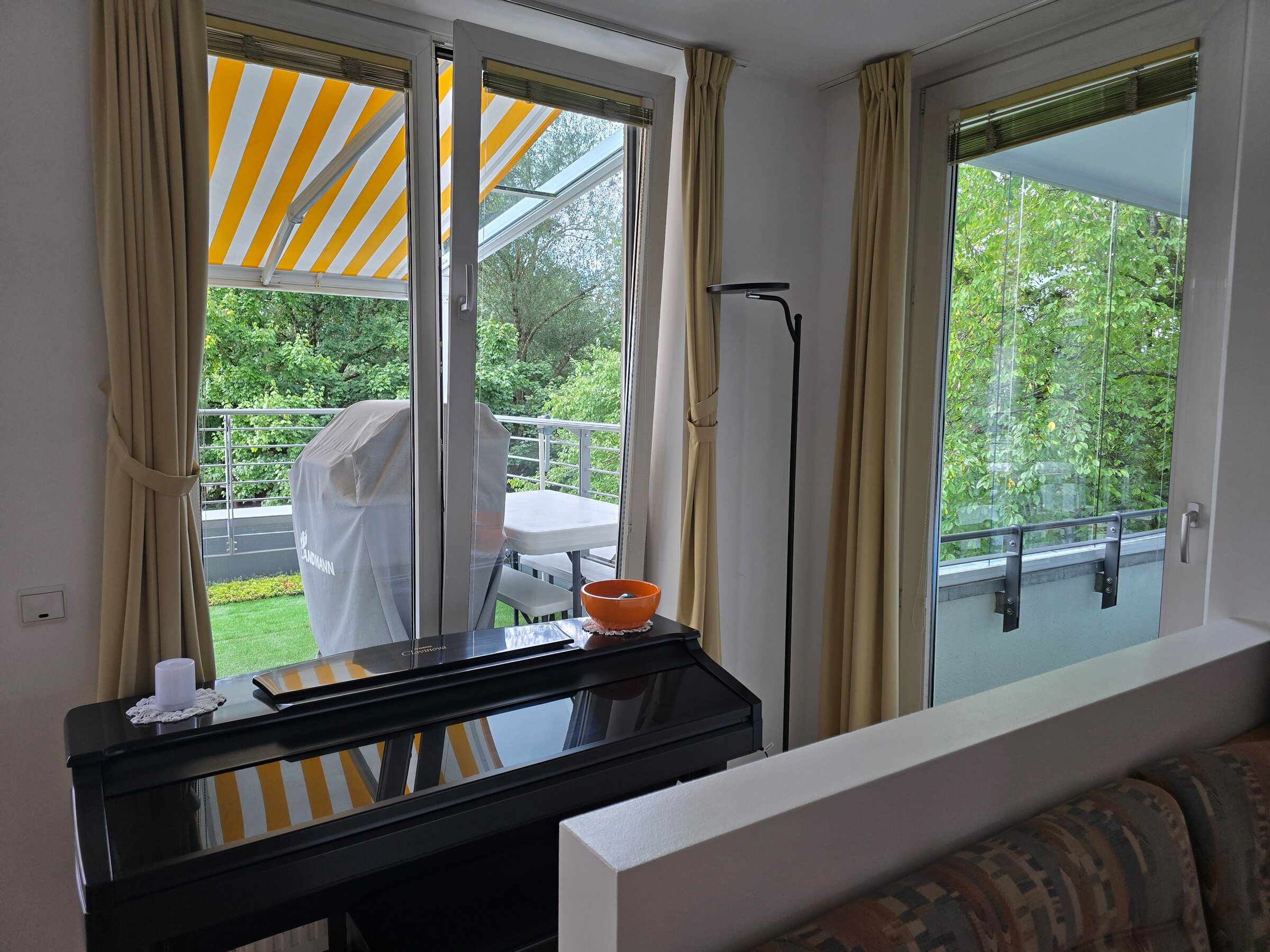 Der Blick vom Essbereich zeigt drei bodentiefe Fenster bzw. Türen nach außen: Links die Terrassentür, in der Mitte ein weiteres Fenster zur Terrasse und ganz rechts die Tür zur verglasten Loggia mit Blick ins Grüne.