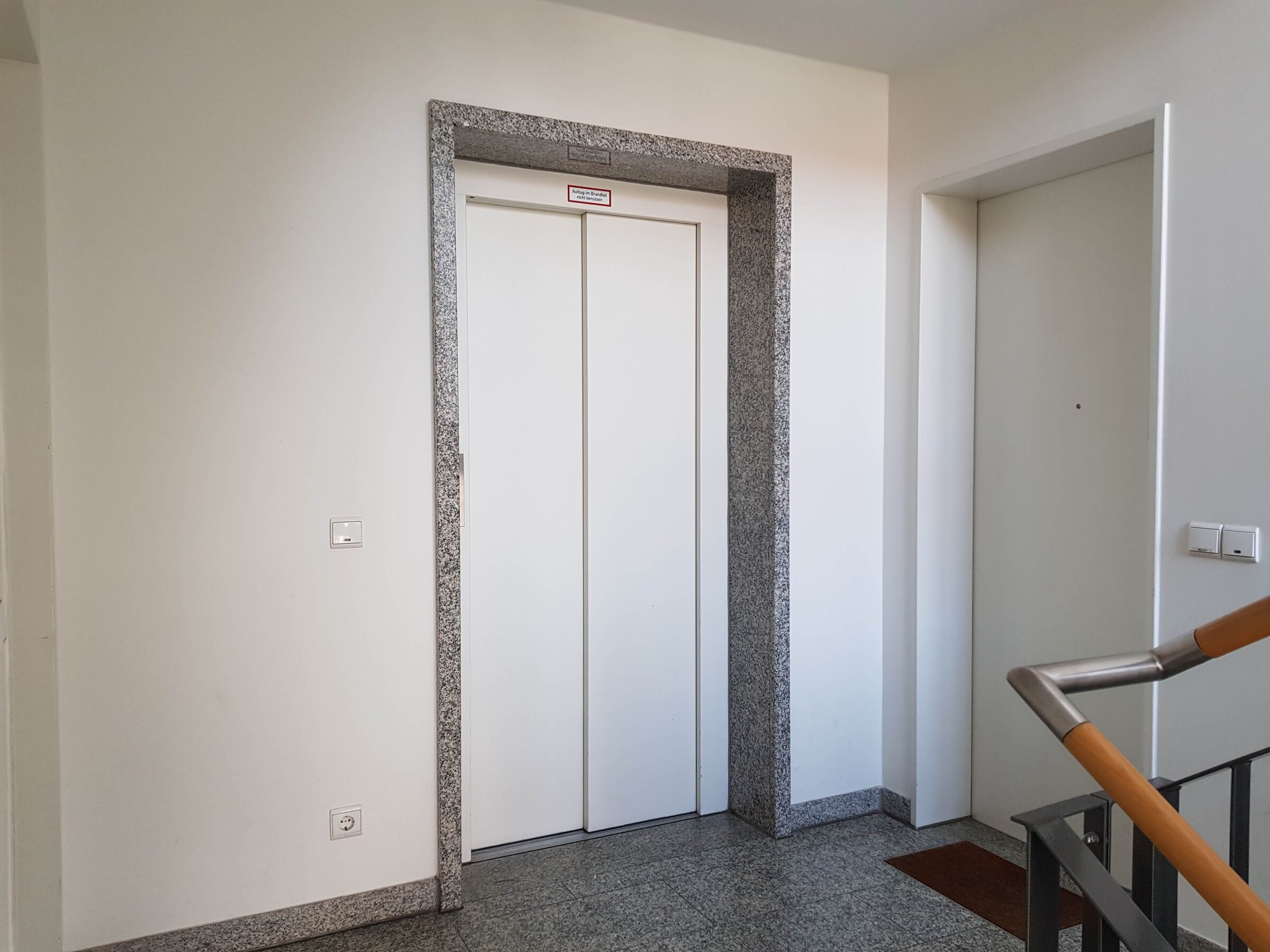 Heller, gepflegter Eingangsbereich im ersten Stock mit direktem Zugang zur Wohnungstür und dem Aufzug.