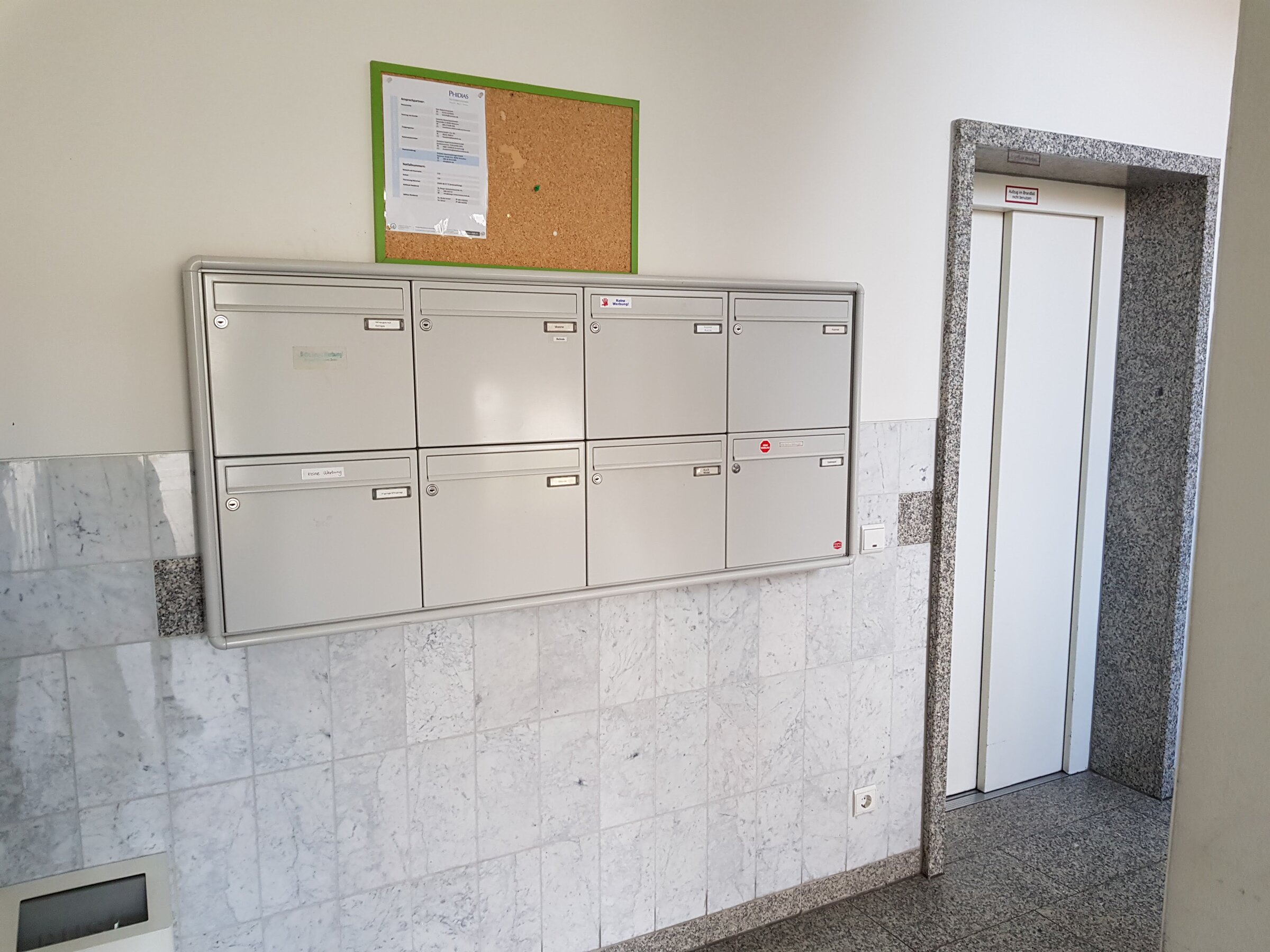 Ordentlicher Eingangsbereich mit Briefkastenanlage und Aufzug im Erdgeschoss des Mehrfamilienhauses.