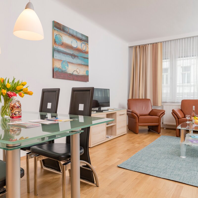 Helles Wohn-Esszimmer mit Glastisch & Ledersofa – 3-Zimmer Wohnung zur Kurzzeitmiete & Wohnen auf Zeit für 1 bis 6 Monate in Wien | © Georg Kaulfersch @georgeye