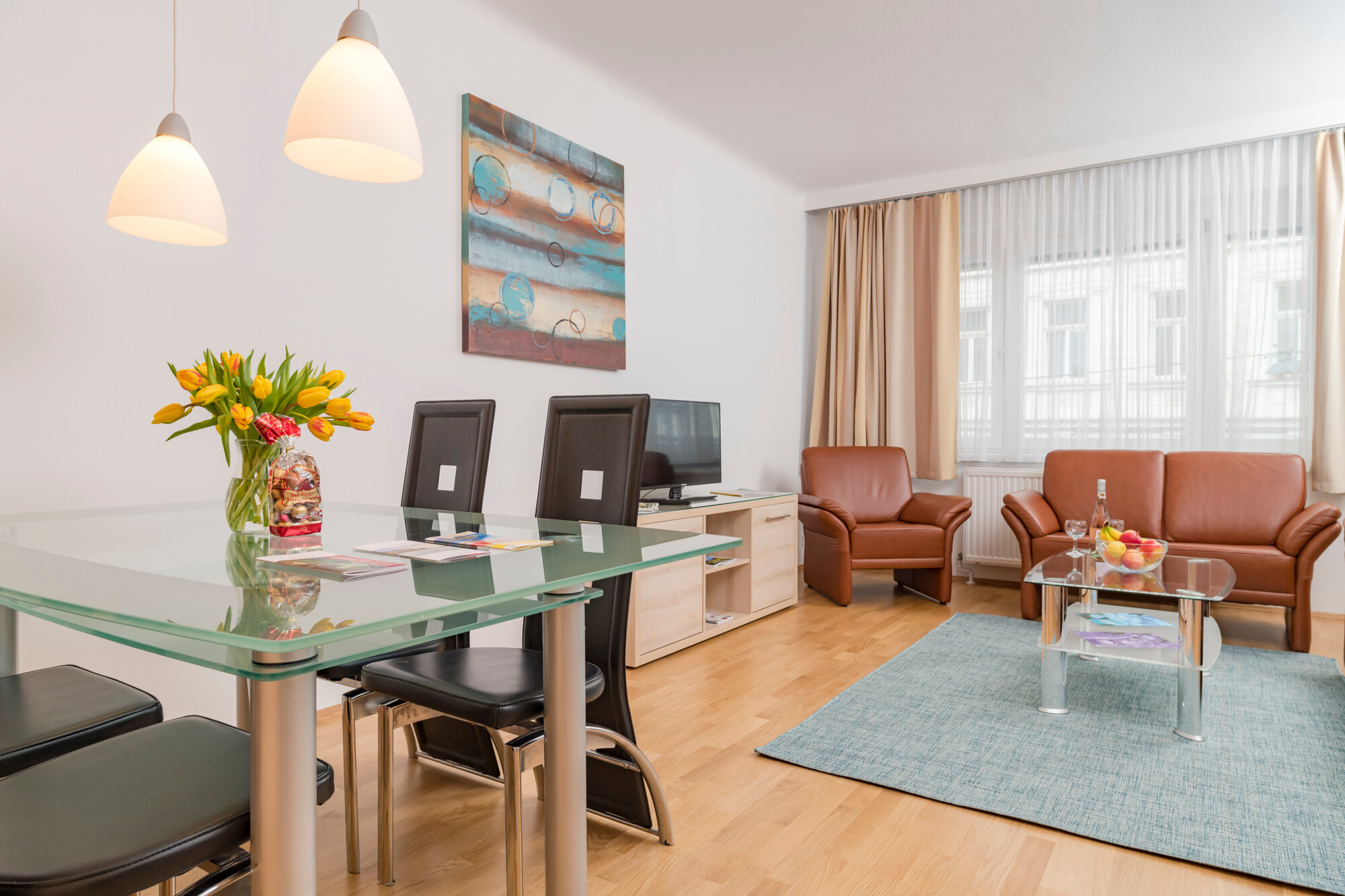 Helles Wohn-Esszimmer mit Glastisch & Ledersofa – 3-Zimmer Wohnung zur Kurzzeitmiete & Wohnen auf Zeit für 1 bis 6 Monate in Wien | © Georg Kaulfersch @georgeye