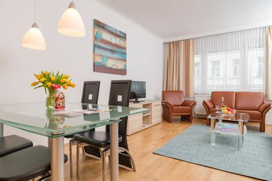 Helles Wohn-Esszimmer mit Glastisch & Ledersofa – 3-Zimmer Wohnung zur Kurzzeitmiete & Wohnen auf Zeit für 1 bis 6 Monate in Wien | © Georg Kaulfersch @georgeye