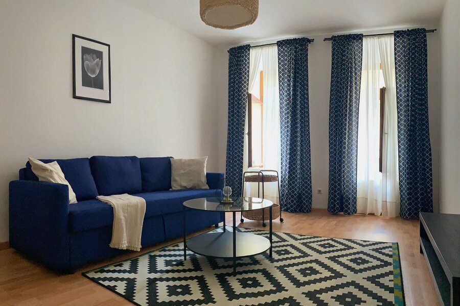 Bright living room, blue sofa & modern decor – 2-room apartment for short-term rental in Vienna, 1 to 6 months | © dilachio