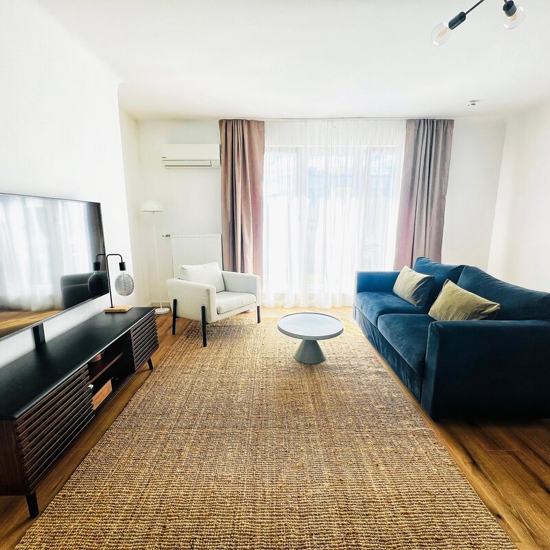 Bright living room with blue sofa & TV – 2-room apartment for short-term rental & temporary housing 1 to 6 months Vienna