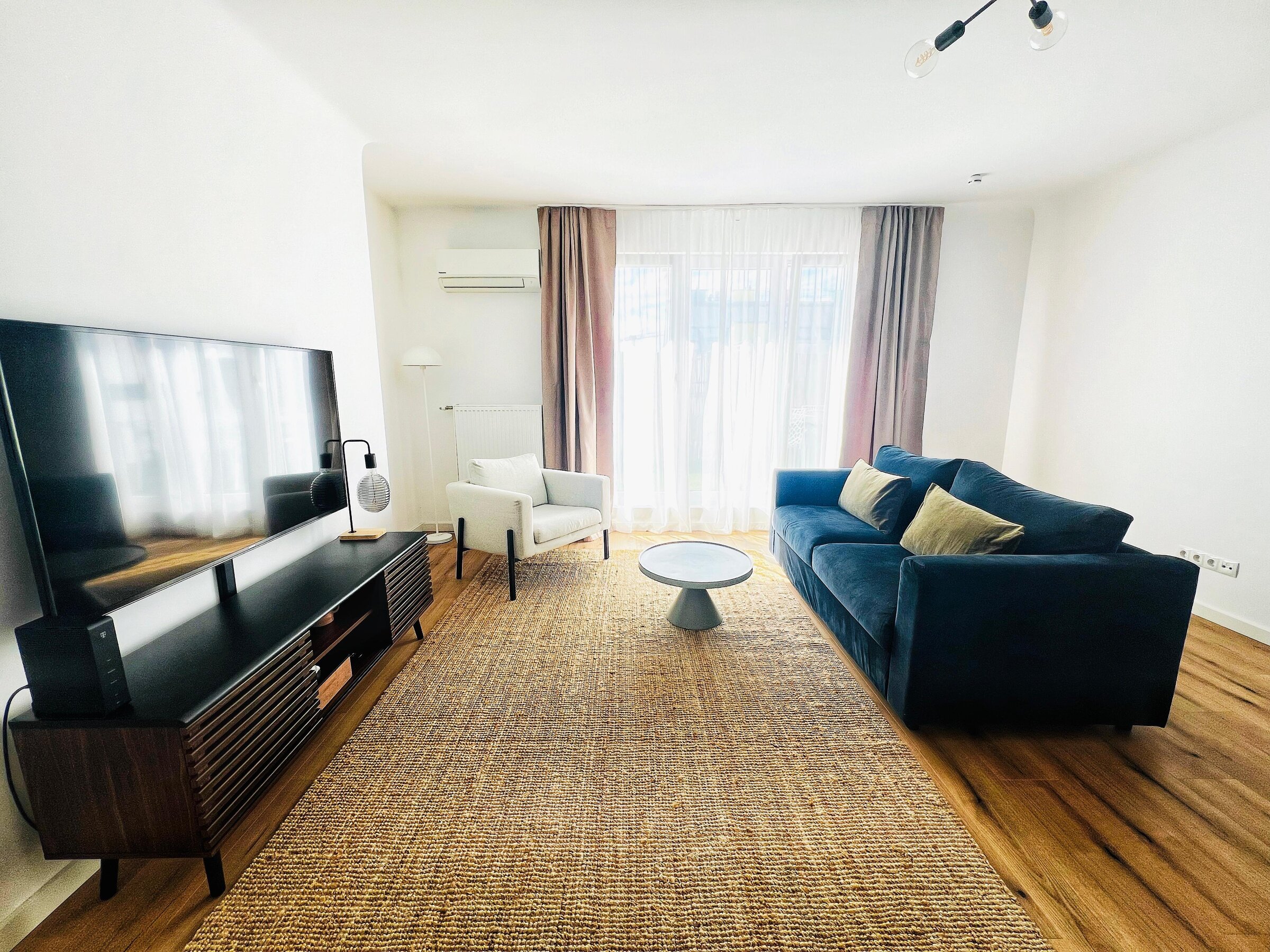 Bright living room with blue sofa & TV – 2-room apartment for short-term rental & temporary housing 1 to 6 months Vienna