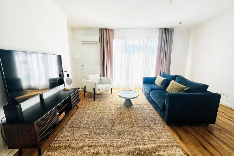Bright living room with blue sofa & TV – 2-room apartment for short-term rental & temporary housing 1 to 6 months Vienna
