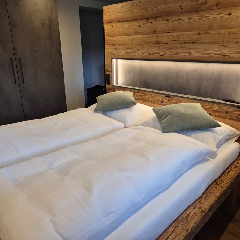 Gemütliches Doppelbett mit Holzwand & LED-Beleuchtung – 1-Zimmer Apartment zur Kurzzeitmiete & Wohnen auf Zeit für 1 bis 6 Monate in Salzburg
