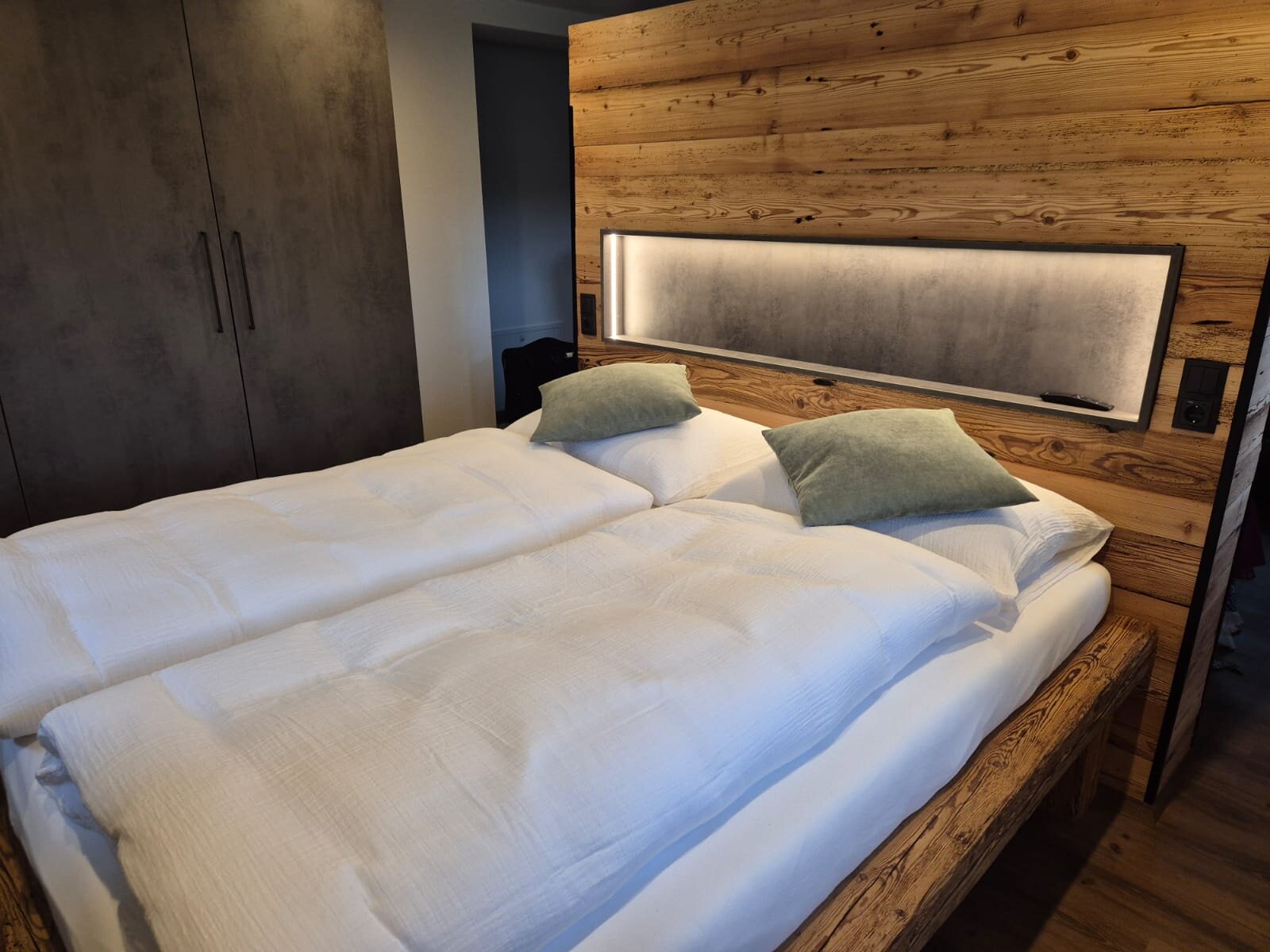 Gemütliches Doppelbett mit Holzwand & LED-Beleuchtung – 1-Zimmer Apartment zur Kurzzeitmiete & Wohnen auf Zeit für 1 bis 6 Monate in Salzburg