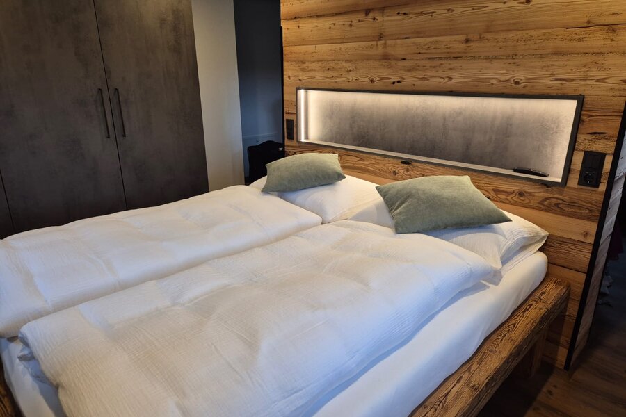 Gemütliches Doppelbett mit Holzwand & LED-Beleuchtung – 1-Zimmer Apartment zur Kurzzeitmiete & Wohnen auf Zeit für 1 bis 6 Monate in Salzburg