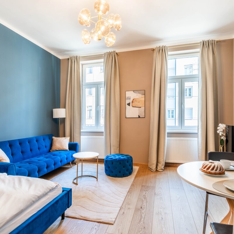 Heller und moderner Wohnbereich eines 5-Sterne Apartments in Wien mit stilvollem Sofa, Essbereich und viel Tageslicht. Ideal für einen komfortablen Aufenthalt nahe U-Bahn und Stadtzentrum.
