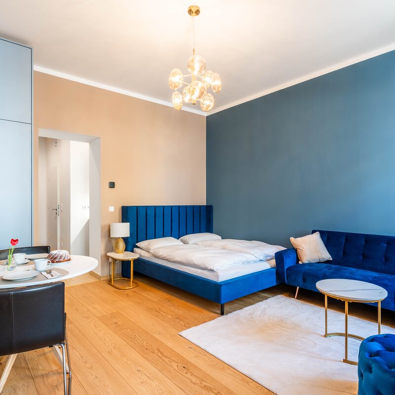 Großzügiger, modern eingerichteter Wohnbereich mit bequemem Bett, Sofa und Essplatz. Helles Design mit viel Tageslicht für einen entspannten Aufenthalt in Wien.