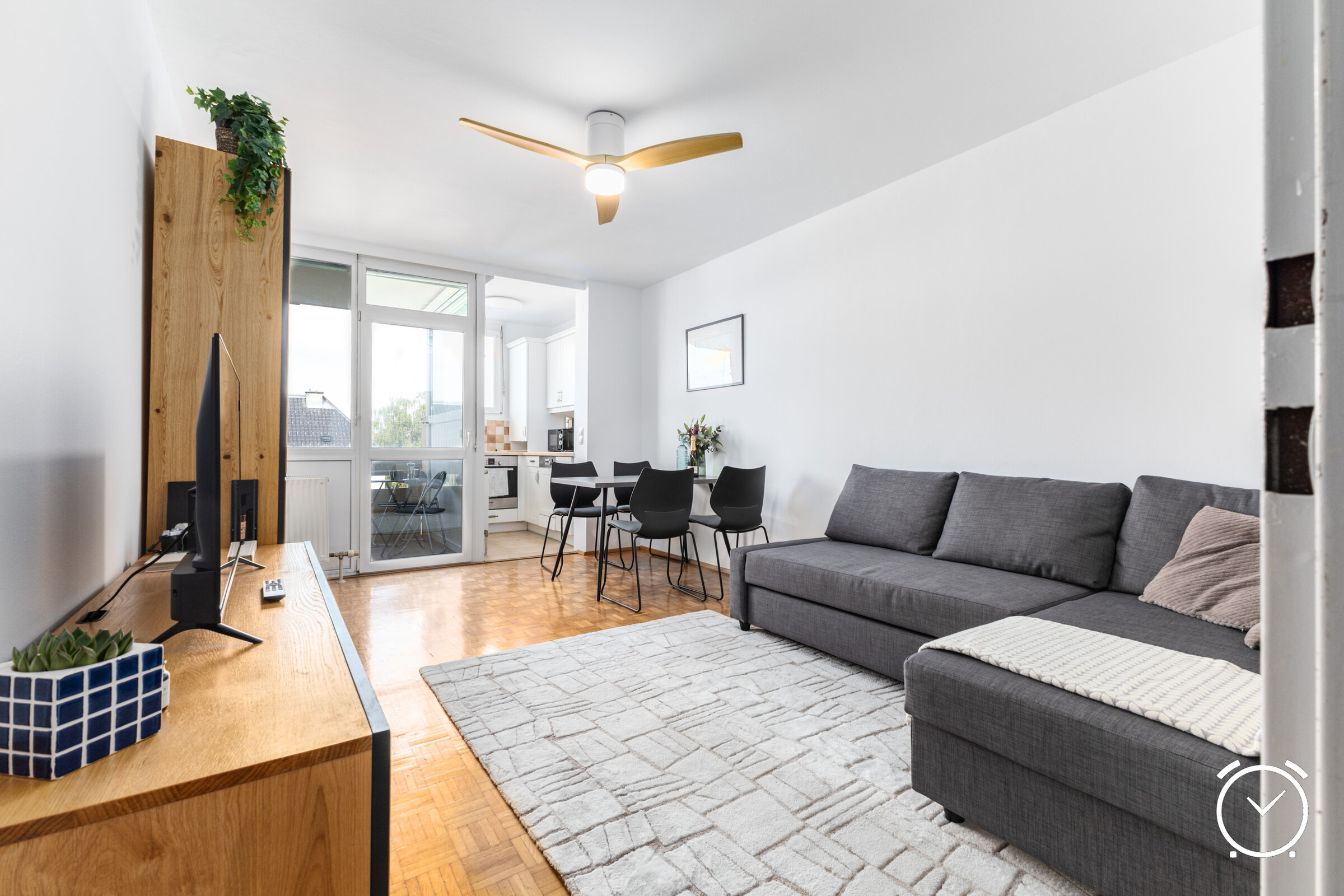 Helles, modern eingerichtetes Wohnzimmer mit gemütlichem Sofa, Essbereich und direktem Zugang zur Küche. Große Fenster sorgen für viel Tageslicht und eine freundliche Atmosphäre.