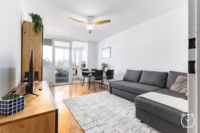 Helles, modern eingerichtetes Wohnzimmer mit gemütlichem Sofa, Essbereich und direktem Zugang zur Küche. Große Fenster sorgen für viel Tageslicht und eine freundliche Atmosphäre.