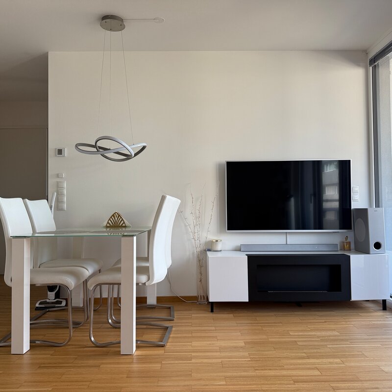 Heller Wohn-Essbereich mit Glasetisch & TV – 2-Zimmer Wohnung, Kurzzeitmiete & Wohnen auf Zeit 1–6 Monate, Wien