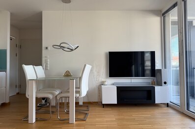 Heller Wohn-Essbereich mit Glasetisch & TV – 2-Zimmer Wohnung, Kurzzeitmiete & Wohnen auf Zeit 1–6 Monate, Wien