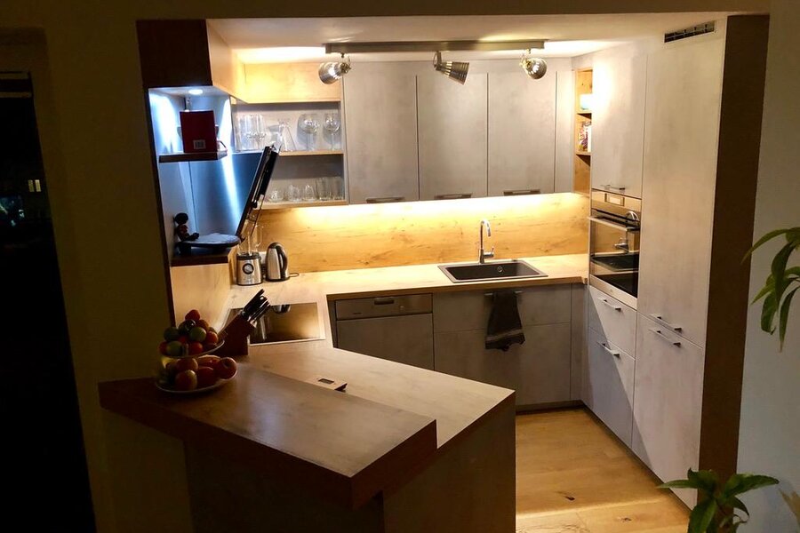 Kitchen with breakfast bar, induction cooktop, dishwasher, large refrigerator and freezer compartment | © Karin Hollenstein