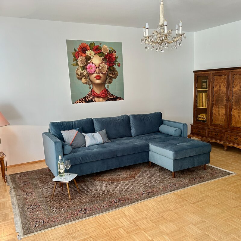 Bright living room with blue sofa & vintage cabinet – 3-room apartment for short-term rental in Klagenfurt