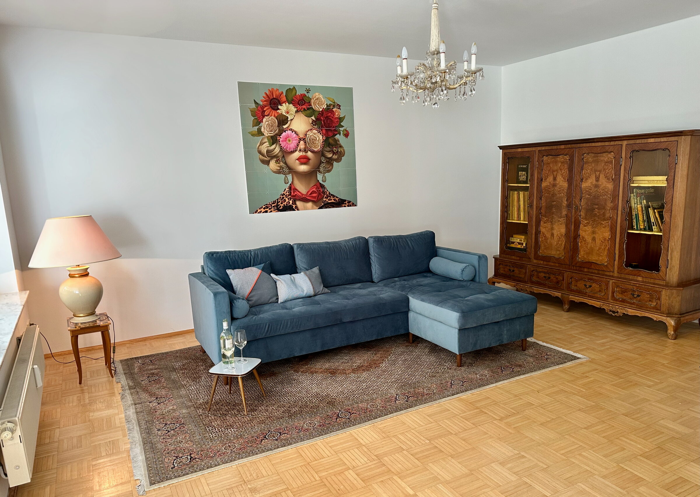 Bright living room with blue sofa & vintage cabinet – 3-room apartment for short-term rental in Klagenfurt