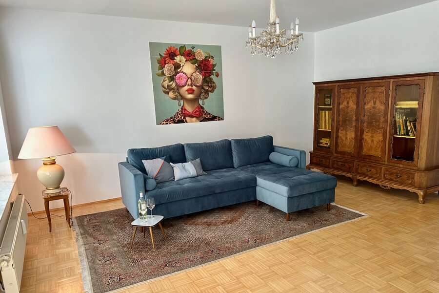 Bright living room with blue sofa & vintage cabinet – 3-room apartment for short-term rental in Klagenfurt