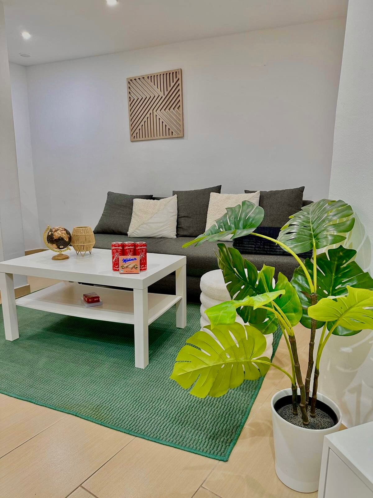 Helles Wohnzimmer mit Monstera & grünem Teppich – 2-Zimmer Wohnung zur Kurzzeitmiete, Wohnen auf Zeit 1 bis 6 Monate, Wien