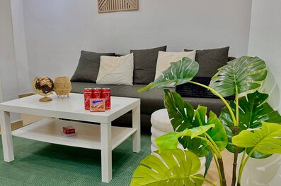 Helles Wohnzimmer mit Monstera & grünem Teppich – 2-Zimmer Wohnung zur Kurzzeitmiete, Wohnen auf Zeit 1 bis 6 Monate, Wien