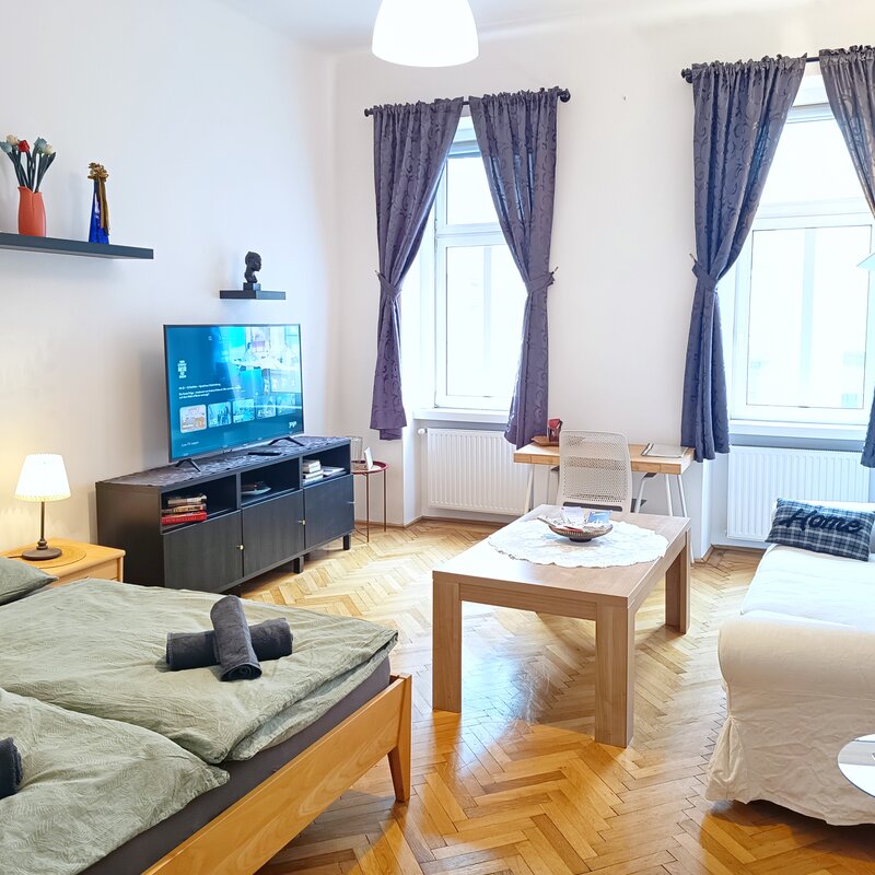 Wohnzimmer mit Doppelbett, Smart TV, Sofa, Arbeitsplatz