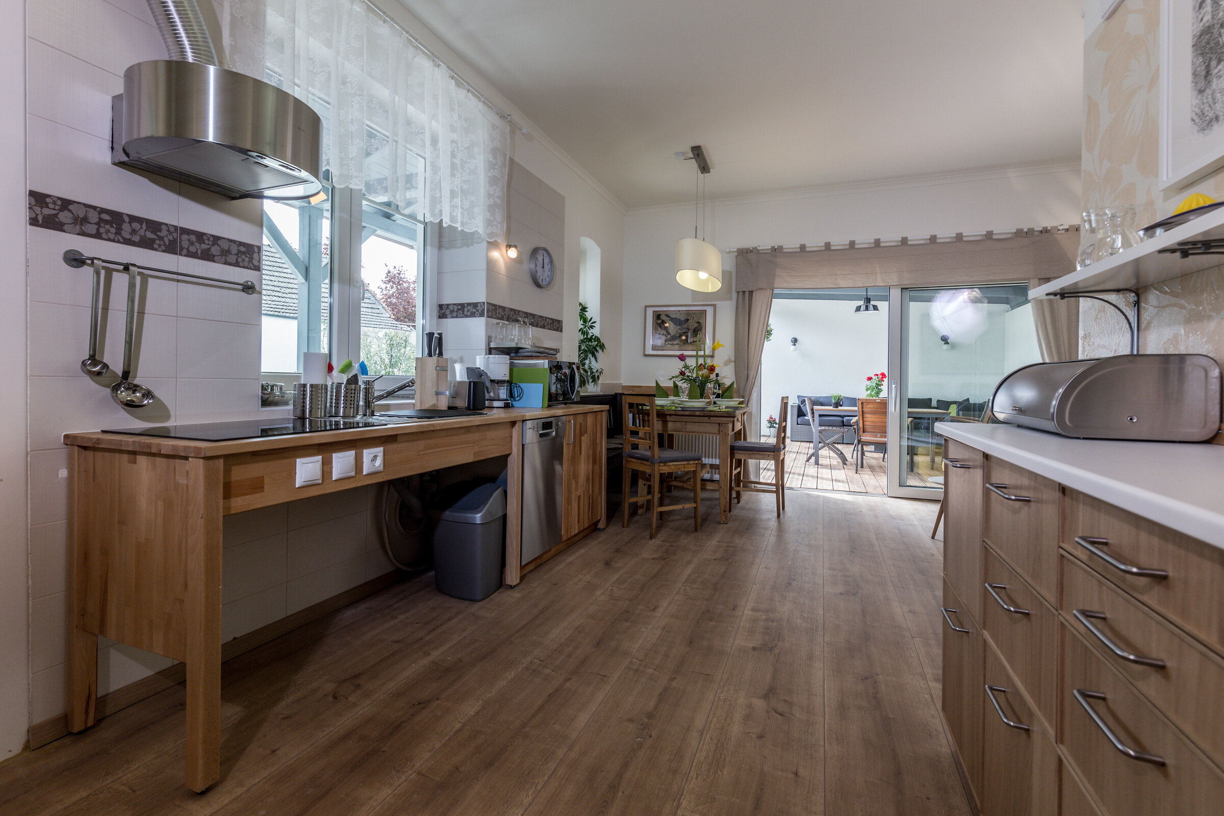 eine barrierefreie Kochstelle, ein Esstisch, die Schiebertür zur Terrasse