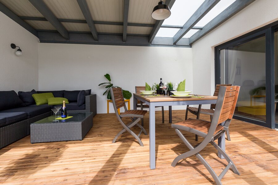 Die Terrase ist zum Innenhof hin offen, rechts die Glastüre zum Wohnzimmer