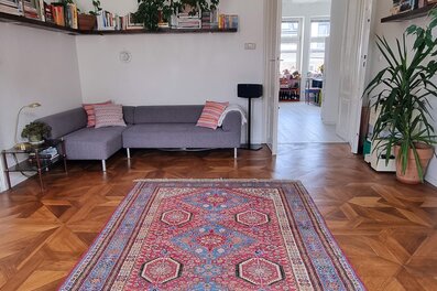 Helles Wohnzimmer mit Parkettboden & Orientteppich – 3-Zimmer Wohnung zur Kurzzeitmiete, Wohnen auf Zeit für 1 bis 6 Monate in Wien | © Luca
