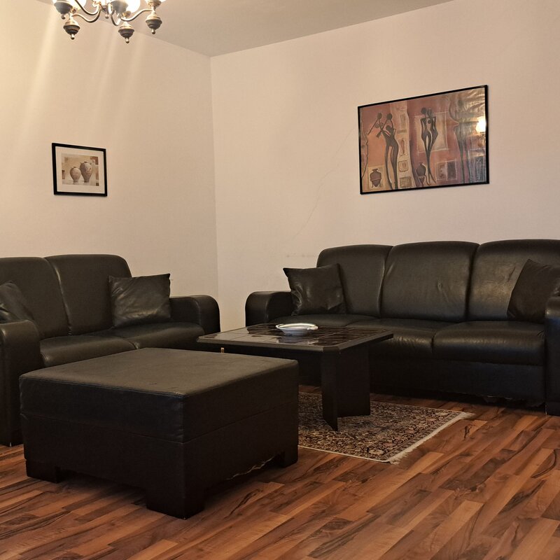 Helles Wohnzimmer mit schwarzen Ledersofas – 3-Zimmer Wohnung zur Kurzzeitmiete, Wohnen auf Zeit 1 bis 6 Monate, Wien