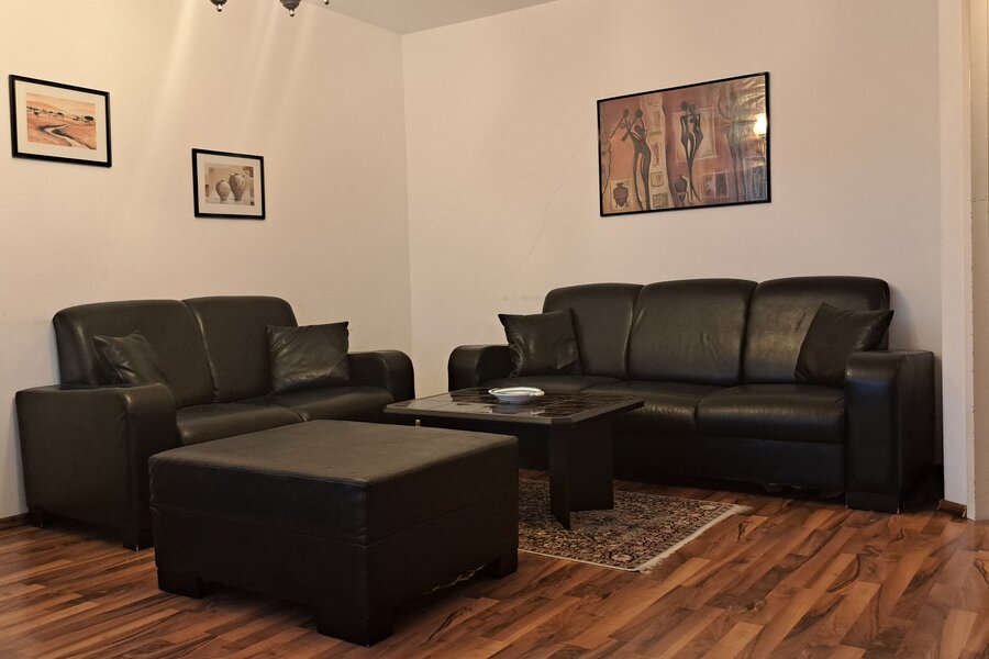 Helles Wohnzimmer mit schwarzen Ledersofas – 3-Zimmer Wohnung zur Kurzzeitmiete, Wohnen auf Zeit 1 bis 6 Monate, Wien