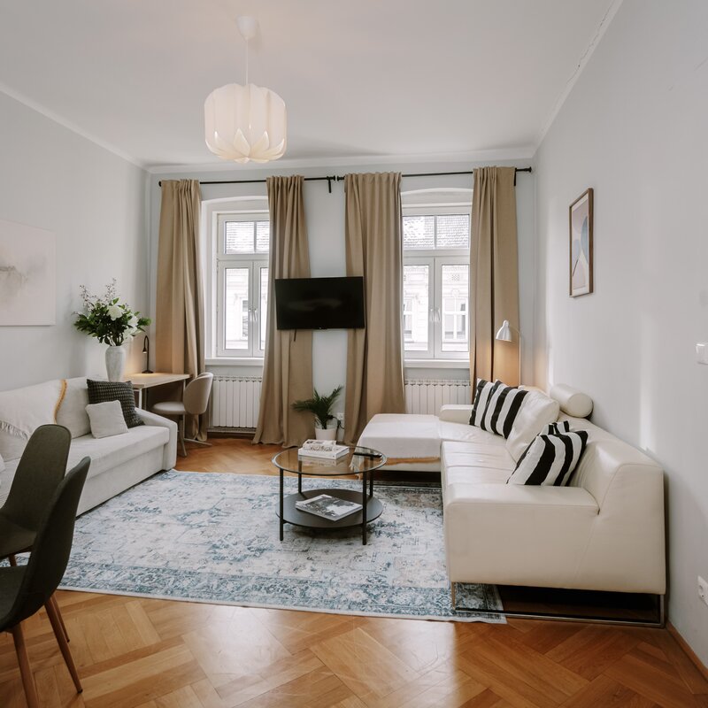 Heller Wohnbereich mit weißer Couch & Parkettboden – 3-Zimmer Wohnung, Kurzzeitmiete Wien, Wohnen auf Zeit 1 bis 6 Monate | © Apartment Care GmbH