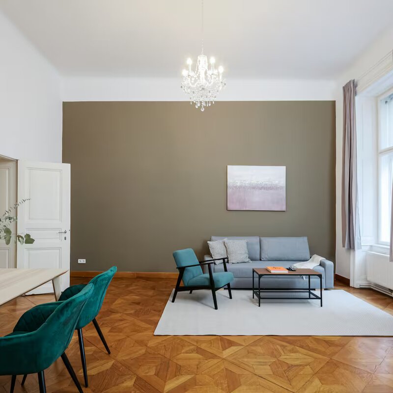 Bright living room with parquet & chandelier – 2-room apartment for short-term rental in Vienna | © Apartment Care GmbH