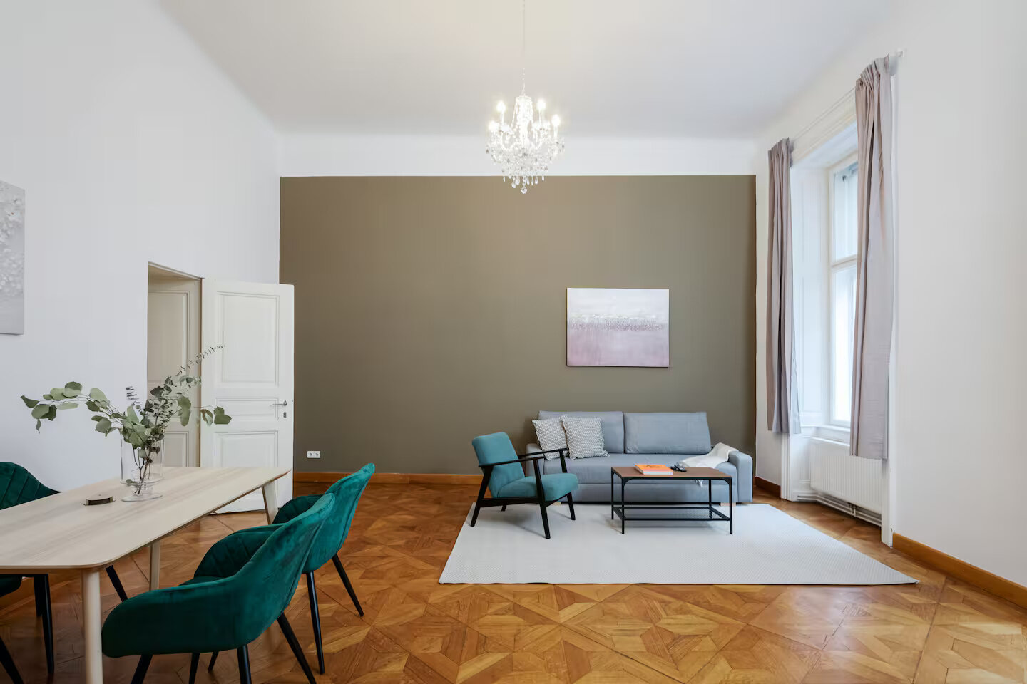 Bright living room with parquet & chandelier – 2-room apartment for short-term rental in Vienna | © Apartment Care GmbH