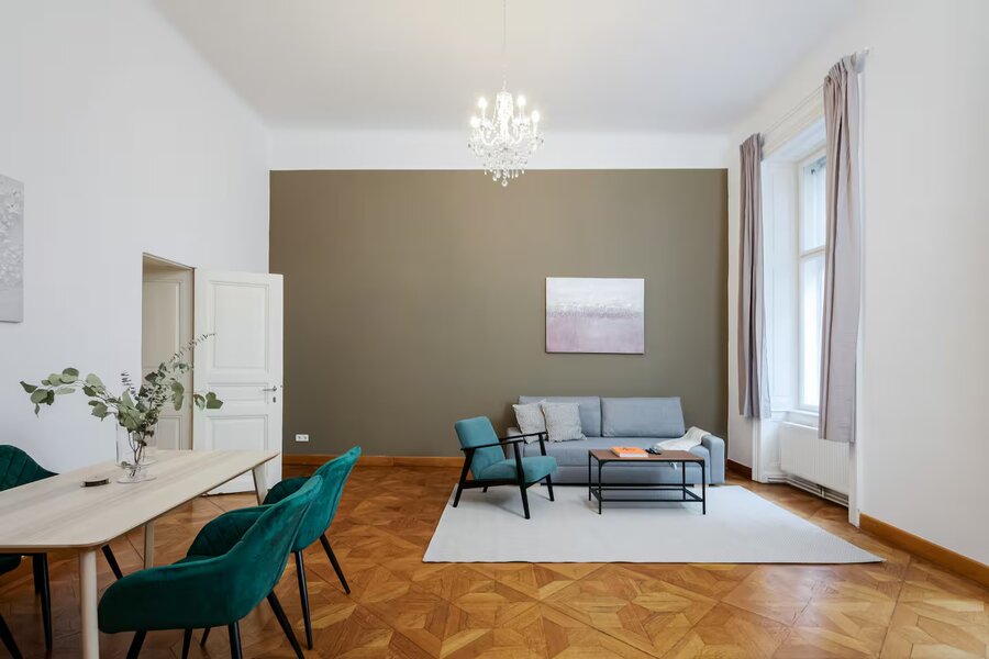 Bright living room with parquet & chandelier – 2-room apartment for short-term rental in Vienna | © Apartment Care GmbH