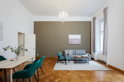 Bright living room with parquet & chandelier – 2-room apartment for short-term rental in Vienna | © Apartment Care GmbH