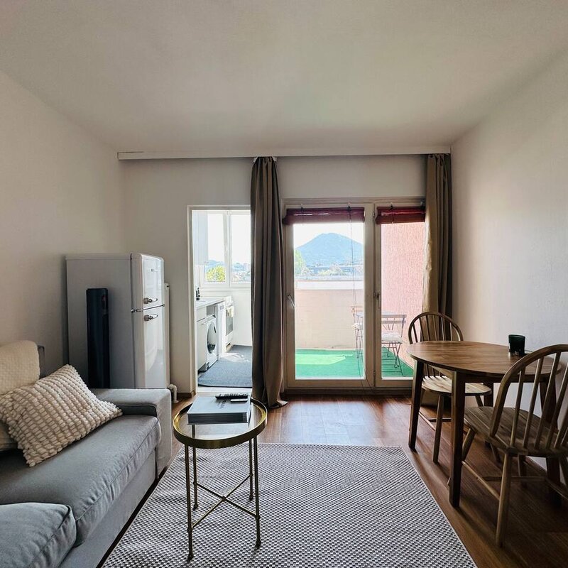 Bright living room with balcony & mountain view – 1-room apt, short-term rental & temporary housing for 1 to 6 months in Salzburg | © Apartment Care GmbH