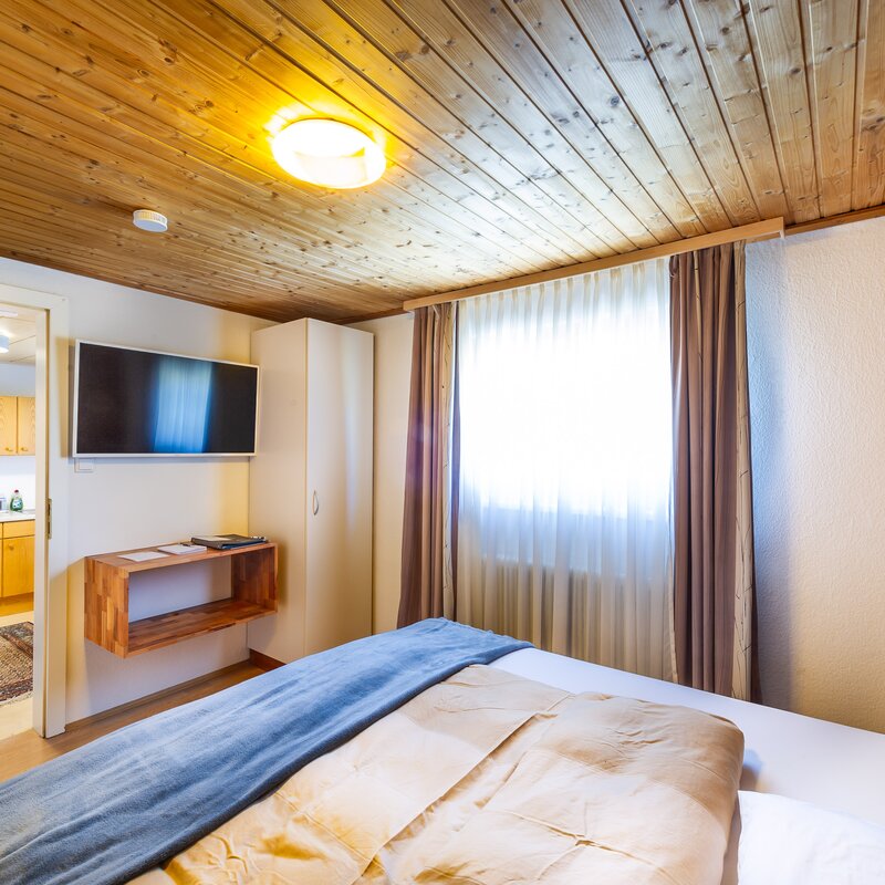 Bright bedroom with wood ceiling & TV in 2-room apartment – short-term rental & temporary housing for 1 to 6 months in Übelbach