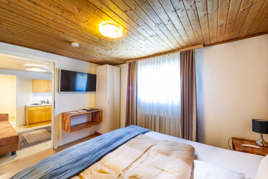 Bright bedroom with wood ceiling & TV in 2-room apartment – short-term rental & temporary housing for 1 to 6 months in Übelbach